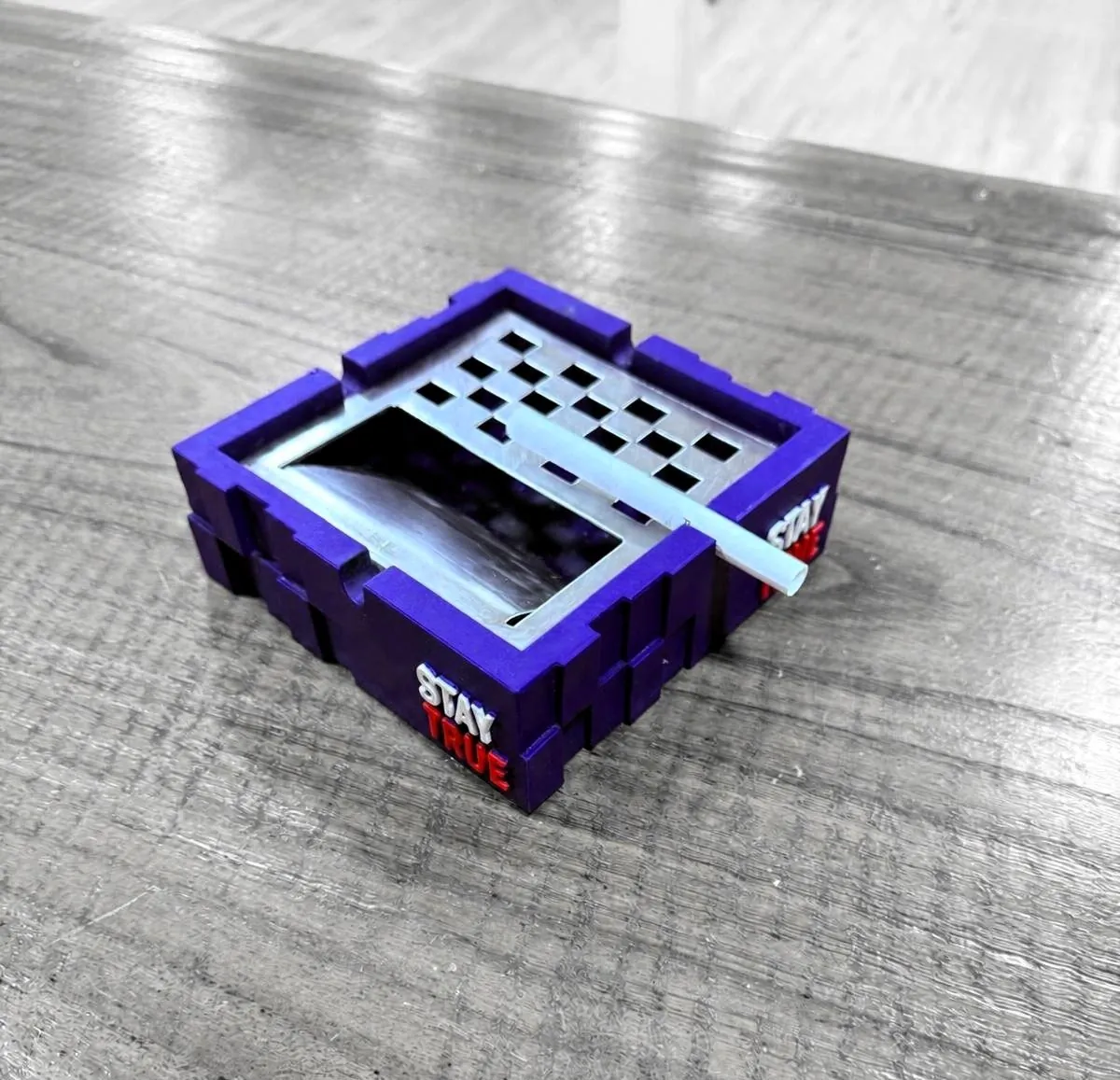 Blau-violette gespritzte Schale in Kistenform mit bedrucktem Panel auf einer grauen Werkbank.