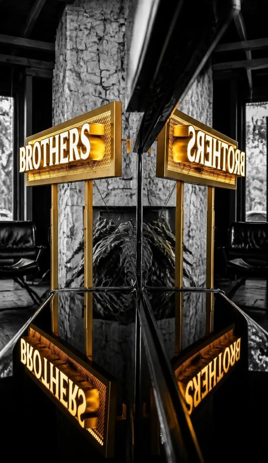 Illuminated gold brand signs projecting from a stone column, doubled in the mirrored ceiling above.